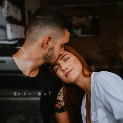 man kissing a woman's forehead as the cuddle