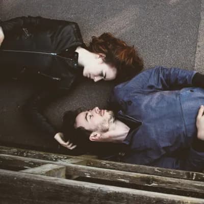 couple laying on the ground while the woman rubs the man's head in loving support