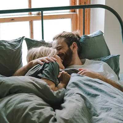 couple smiling in bed after spontaneous sex